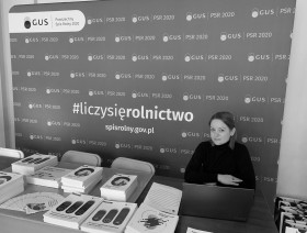 Stoisko z pracownikiem i publikacjami Urzędu Statystycznego w Krakowie na tle ścianki spisowej